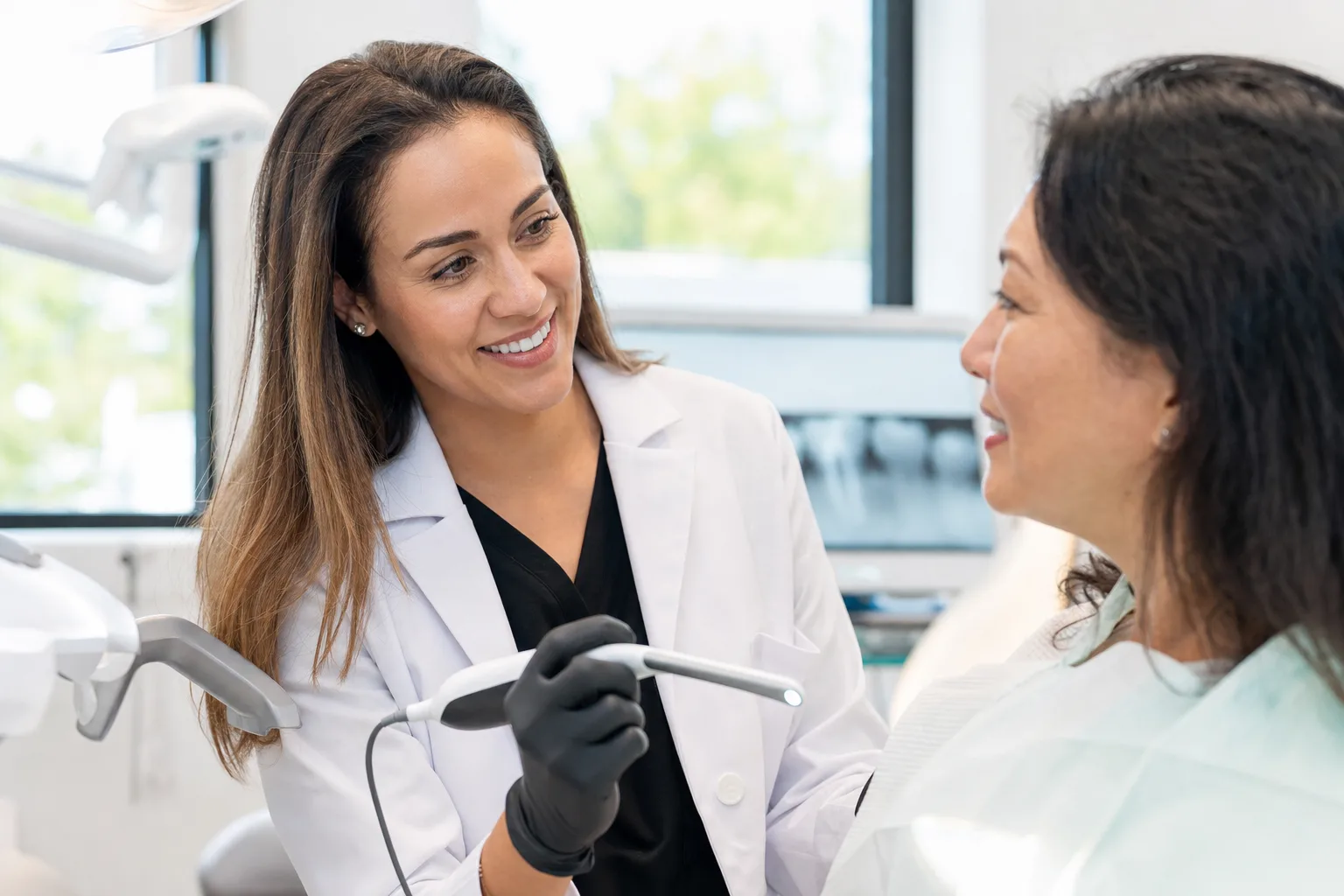Dr. Maya Castellano warmly explaining a treatment plan to a patient in a bright treatment room